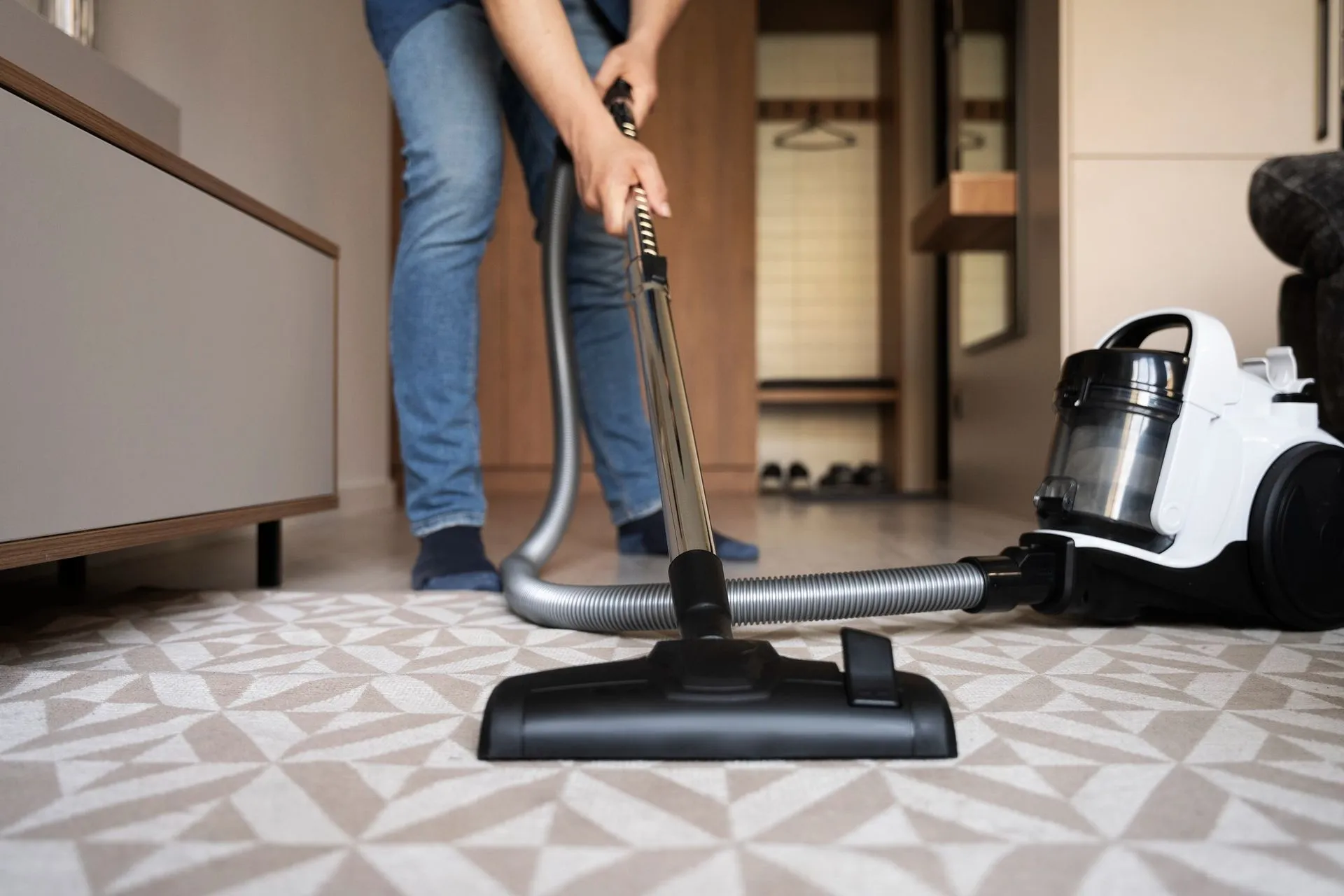 A person is using a vacuum cleaner to clean the floor in a living room.