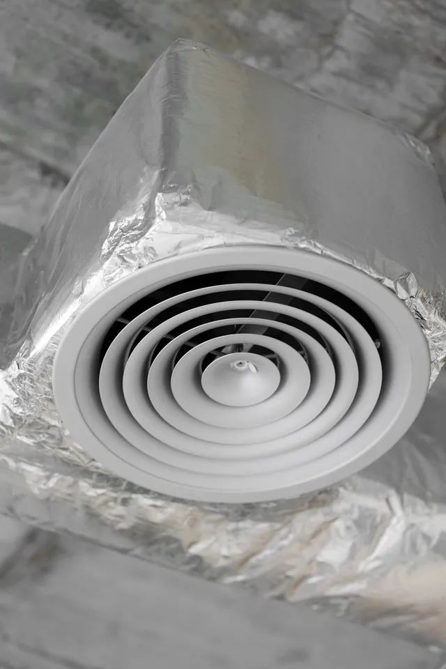 A close up of a white air vent wrapped in aluminum foil.
