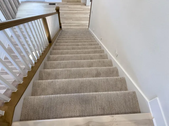 A staircase with clean carpeted steps and a wooden railing in Vancouver