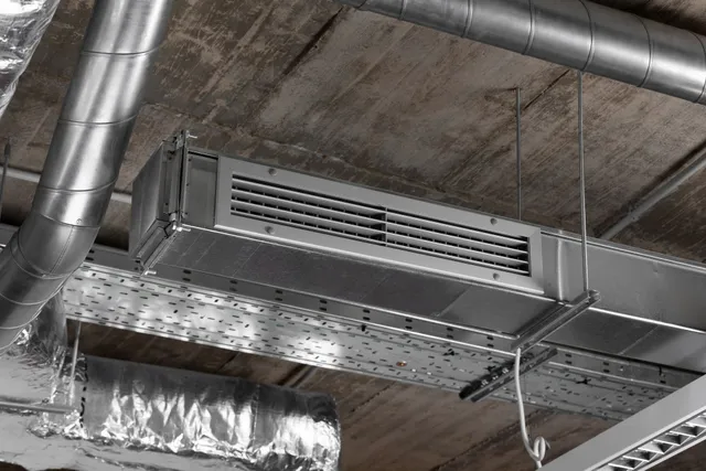 A ceiling with a lot of pipes and ducts hanging from it.