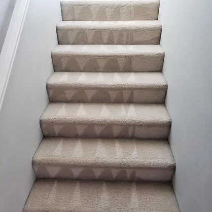 Carpeted staircase with beige-patterned runner and white walls leading upward in Rock Castle