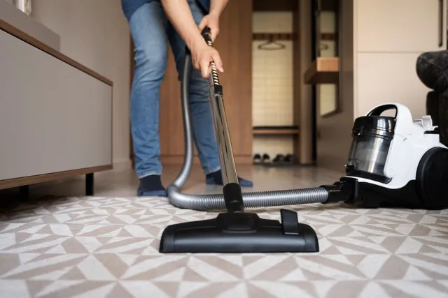 A person is vacuuming the carpet in a living room.